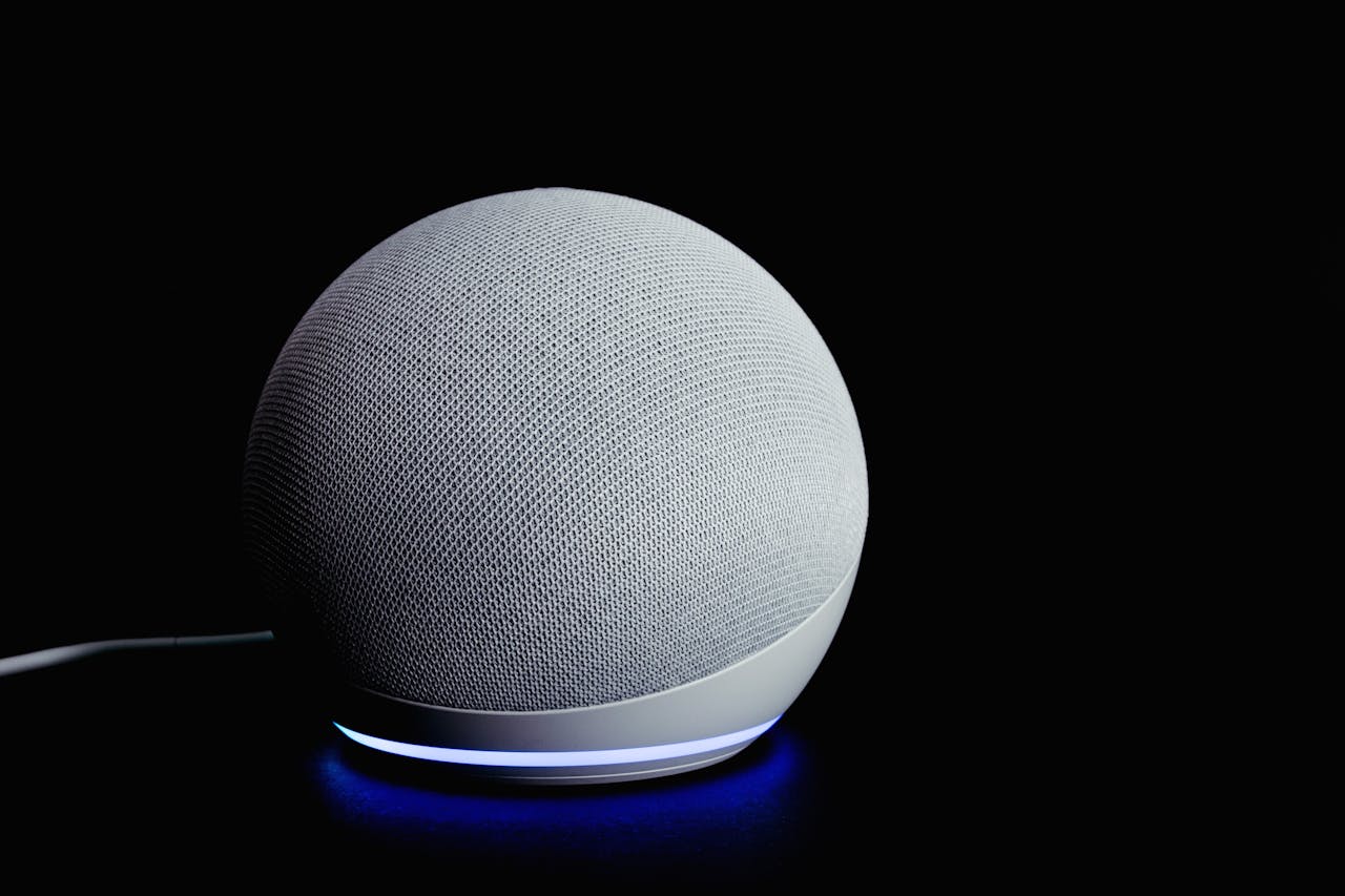 Modern smart speaker device with illuminated ring, featured on a dark background.