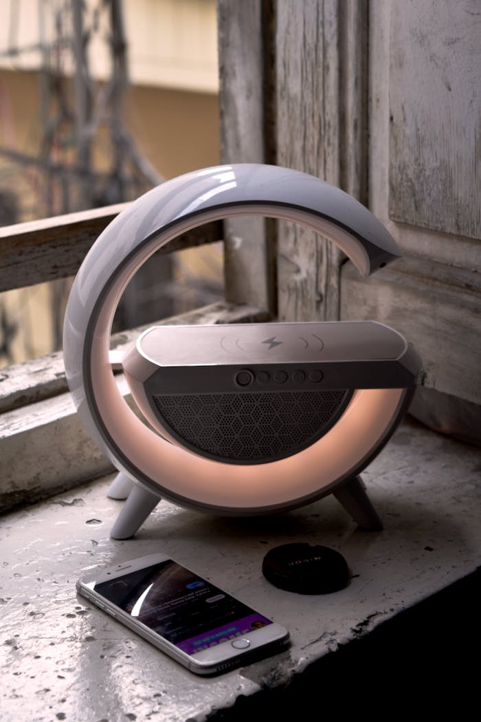 Contemporary speaker with smartphone on rustic windowsill, blending vintage and modern aesthetics.